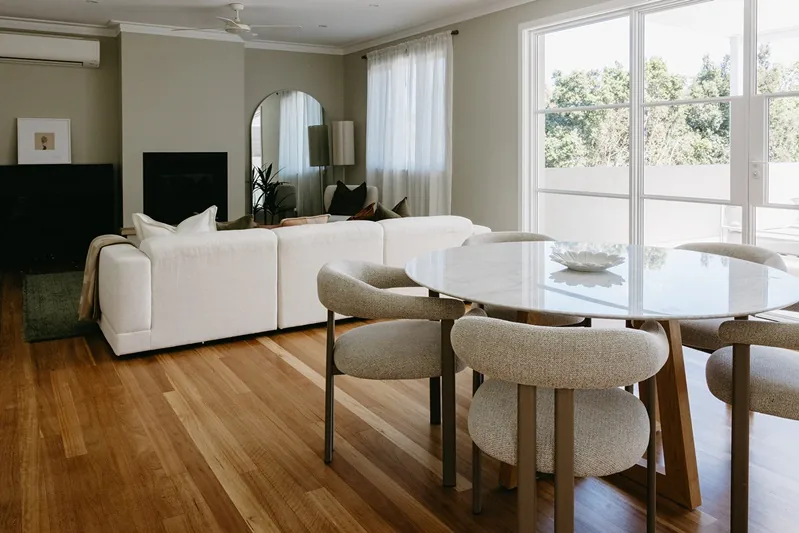 Renewed living and dining room with timber floors and slim-profile French doors